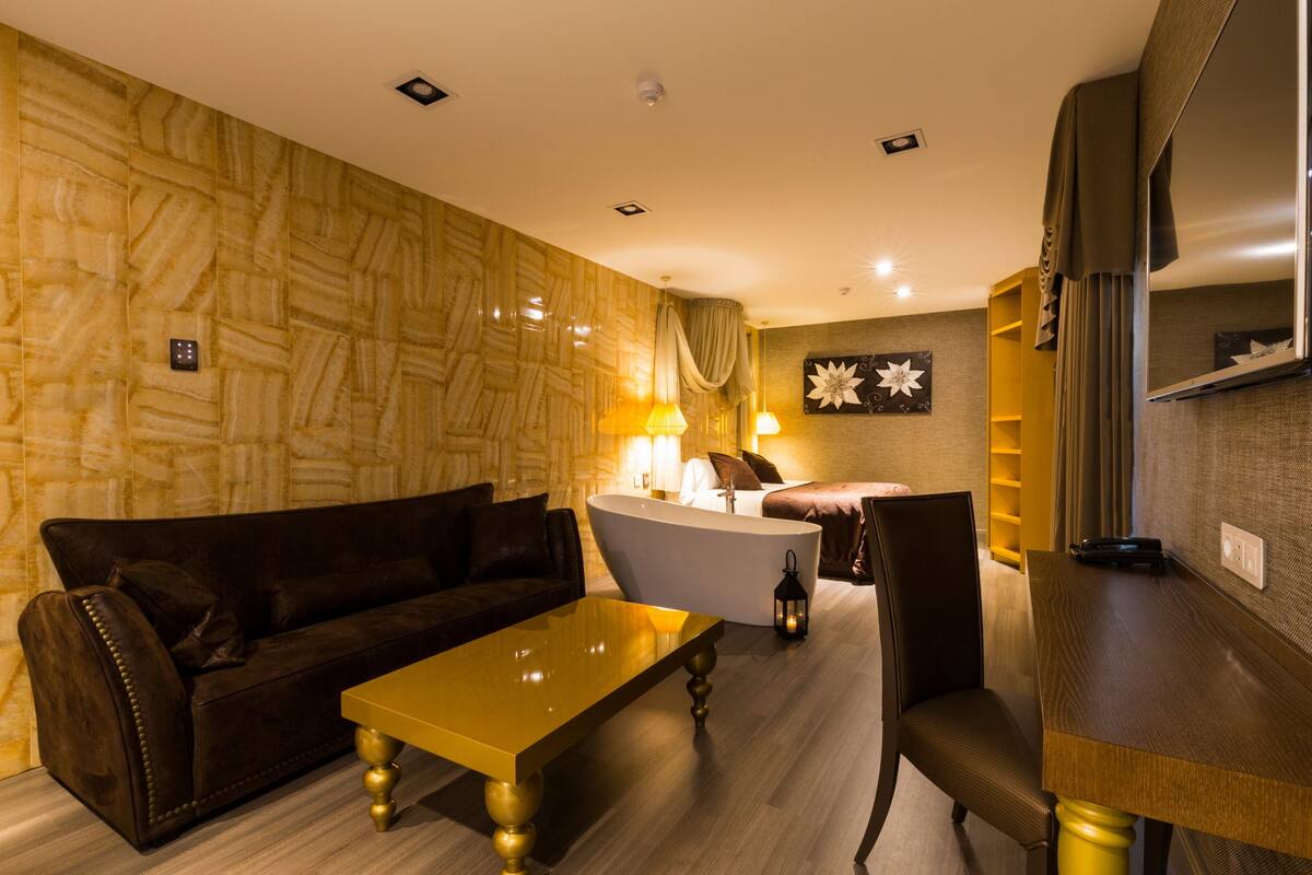 A modern living room with a sofa, a coffee table, a bathtub, and a dining area.