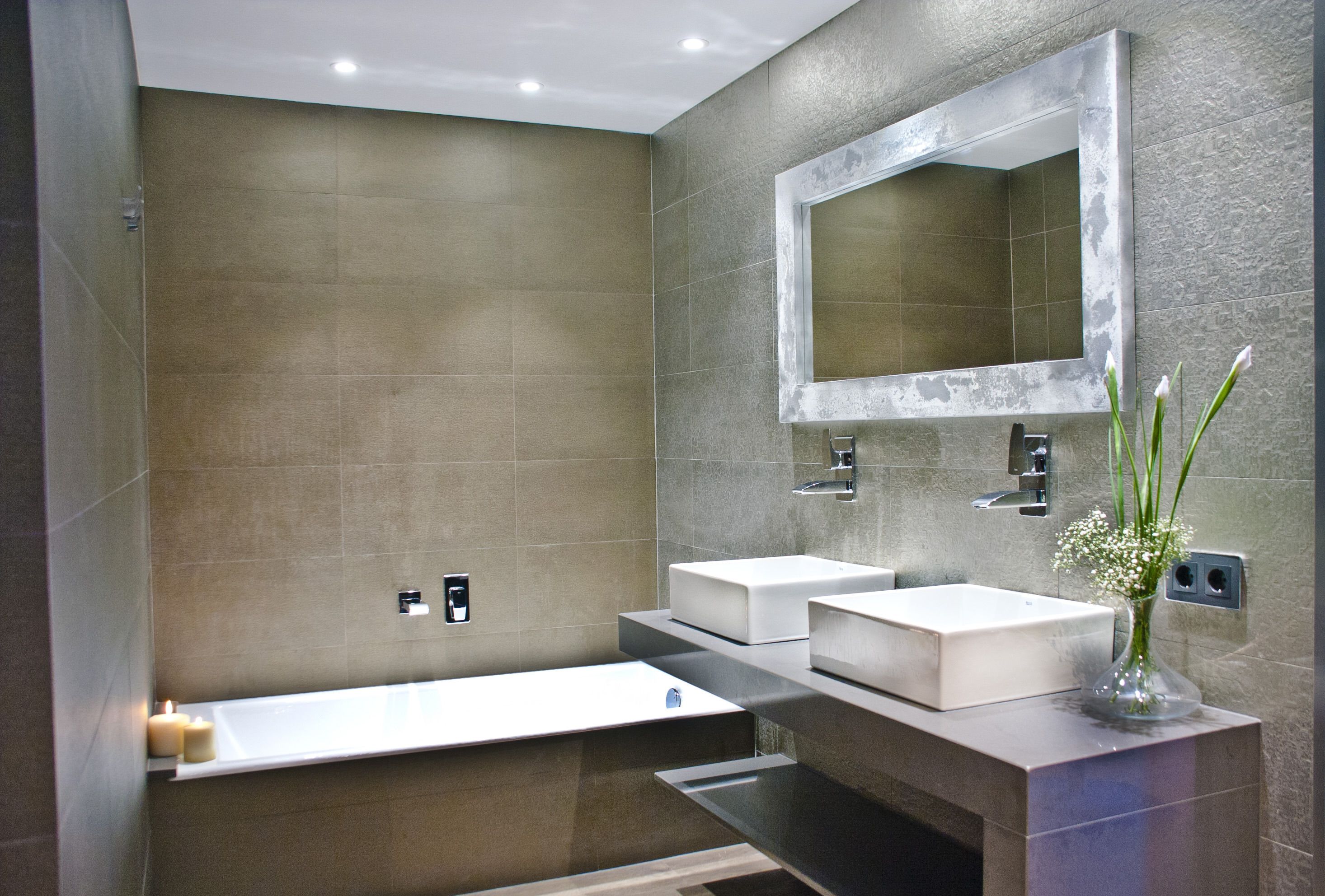 Un baño moderno con dos lavamanos, un espejo grande y una bañera.