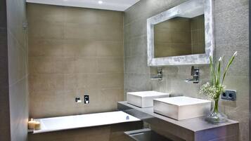 Un baño moderno con dos lavamanos, un espejo grande y una bañera.