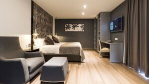 Una habitación de hotel moderna con una cama, un escritorio, una silla y un televisor.