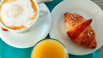 A tray with a cup of coffee, a croissant, and a glass of orange juice.