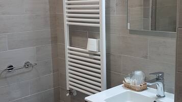 Un baño moderno con un bidé, un perchero blanco, un espejo y un mueble de madera oscura.