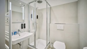 A modern bathroom with a glass-enclosed shower, a white sink, and a toilet. - Urban Rooms Rathaus - Self Check-In (Vienna)