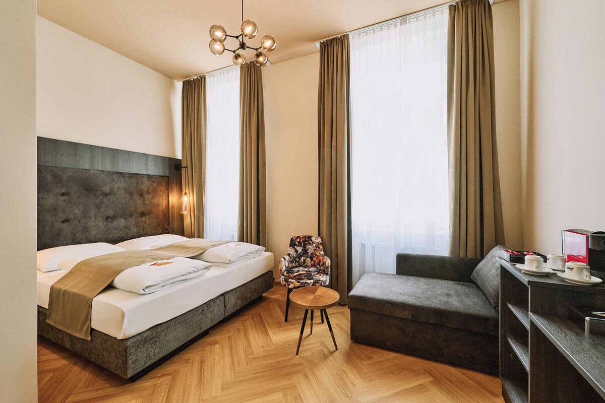 Une chambre d’hôtel moderne avec un grand lit, un canapé, une petite table ronde et une chaise.
