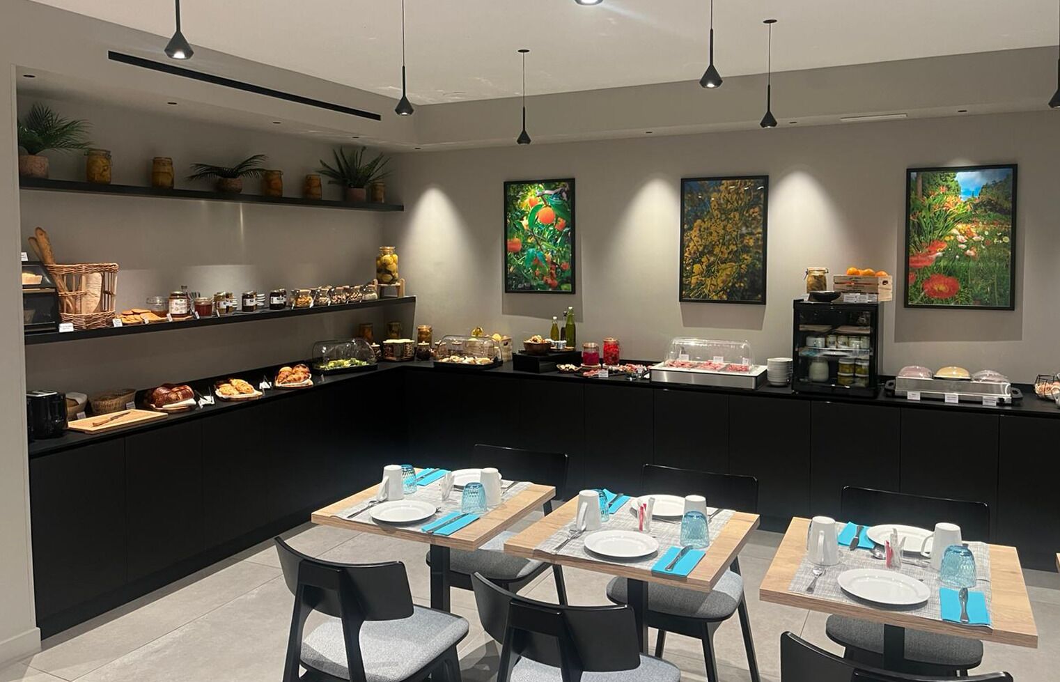 Un comedor moderno con una barra curva, bufé con diferentes comidas y tres cuadros en la pared.