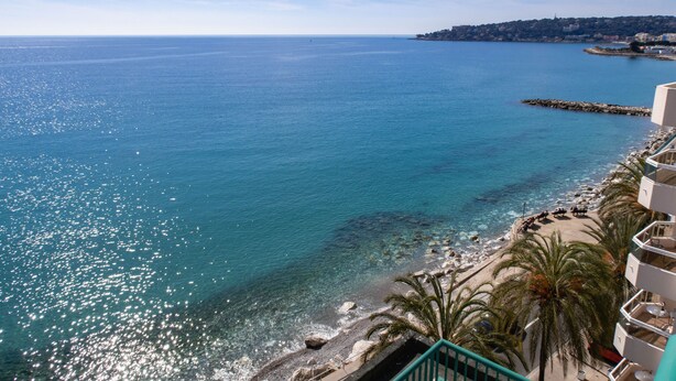 A coastal hotel with a balcony overlooking the sea, a sandy beach, and a rocky shoreline. - Princess et Richmond (Menton)
