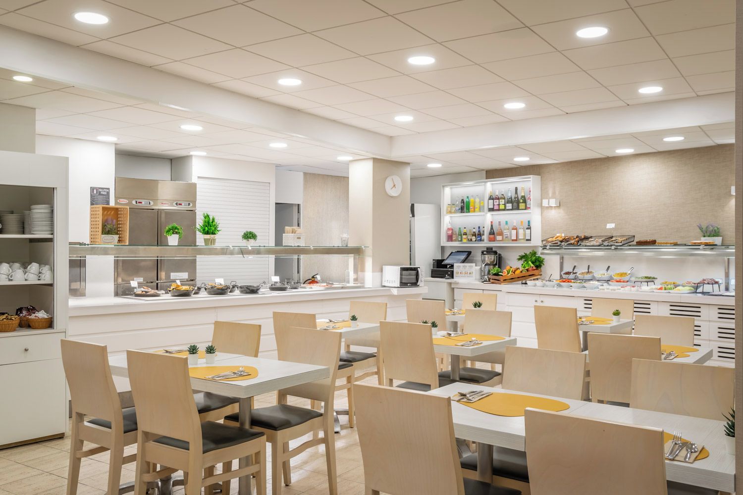 Une cafétéria moderne dotée de nombreuses tables et chaises, d’un espace buffet proposant divers plats et d’un coin café.