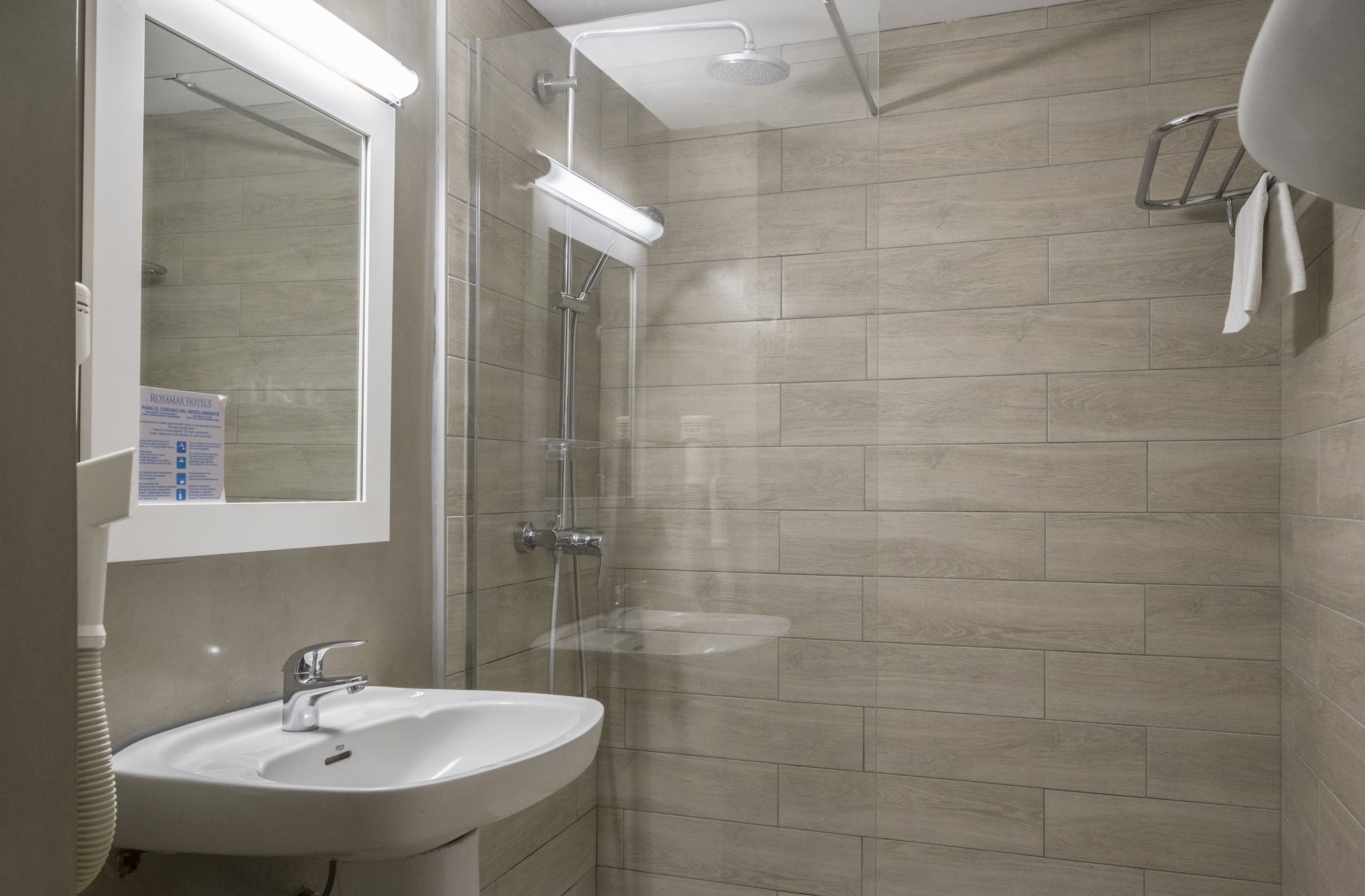 A modern bathroom with a sink, mirror, and shower.