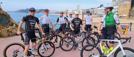 Un grupo de ciclistas con bicicletas, un paisaje costero y edificios.