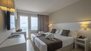 Habitación de hotel con dos camas, un escritorio, una silla, un televisor y una ventana con cortinas.