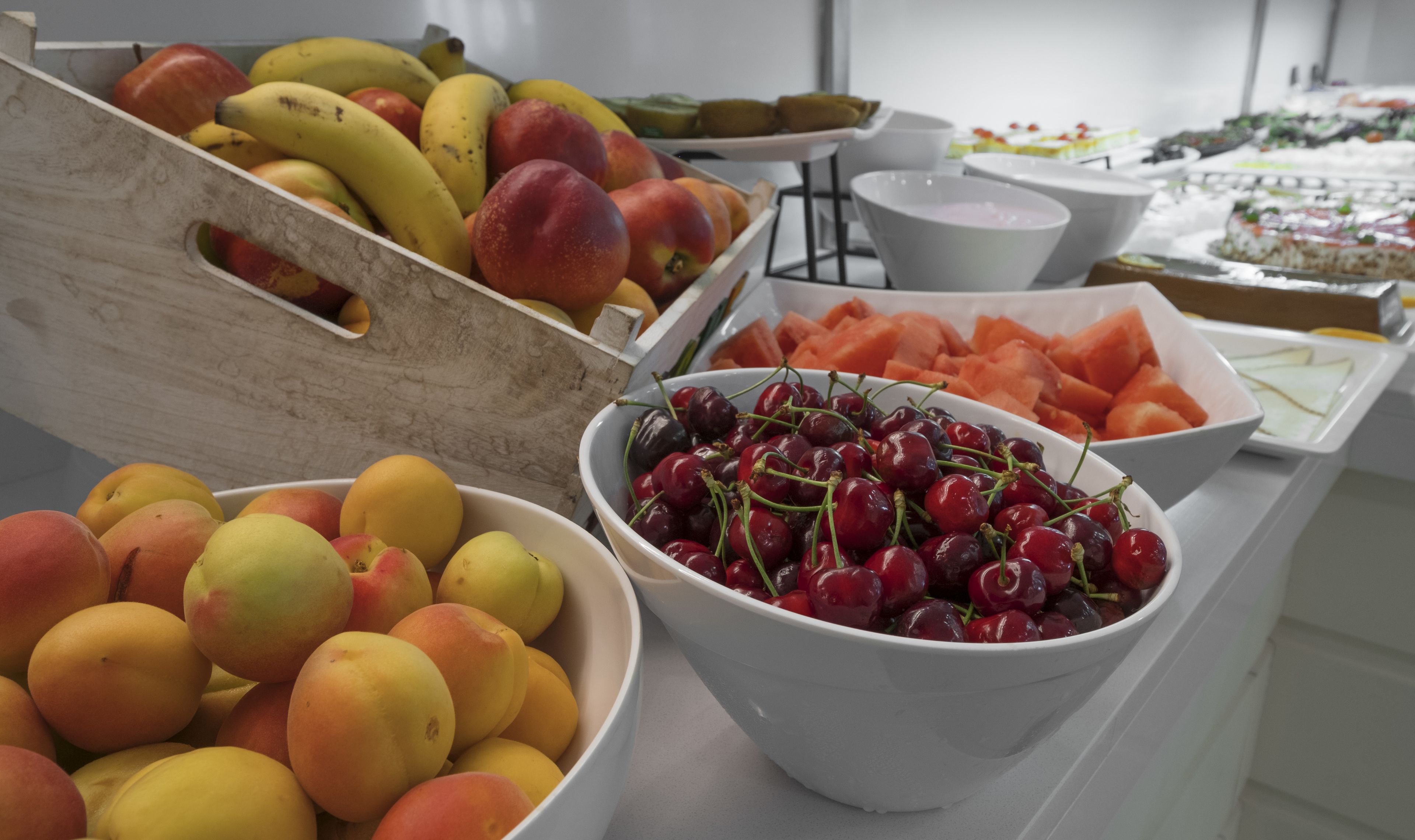 A buffet table with various fruits and desserts.