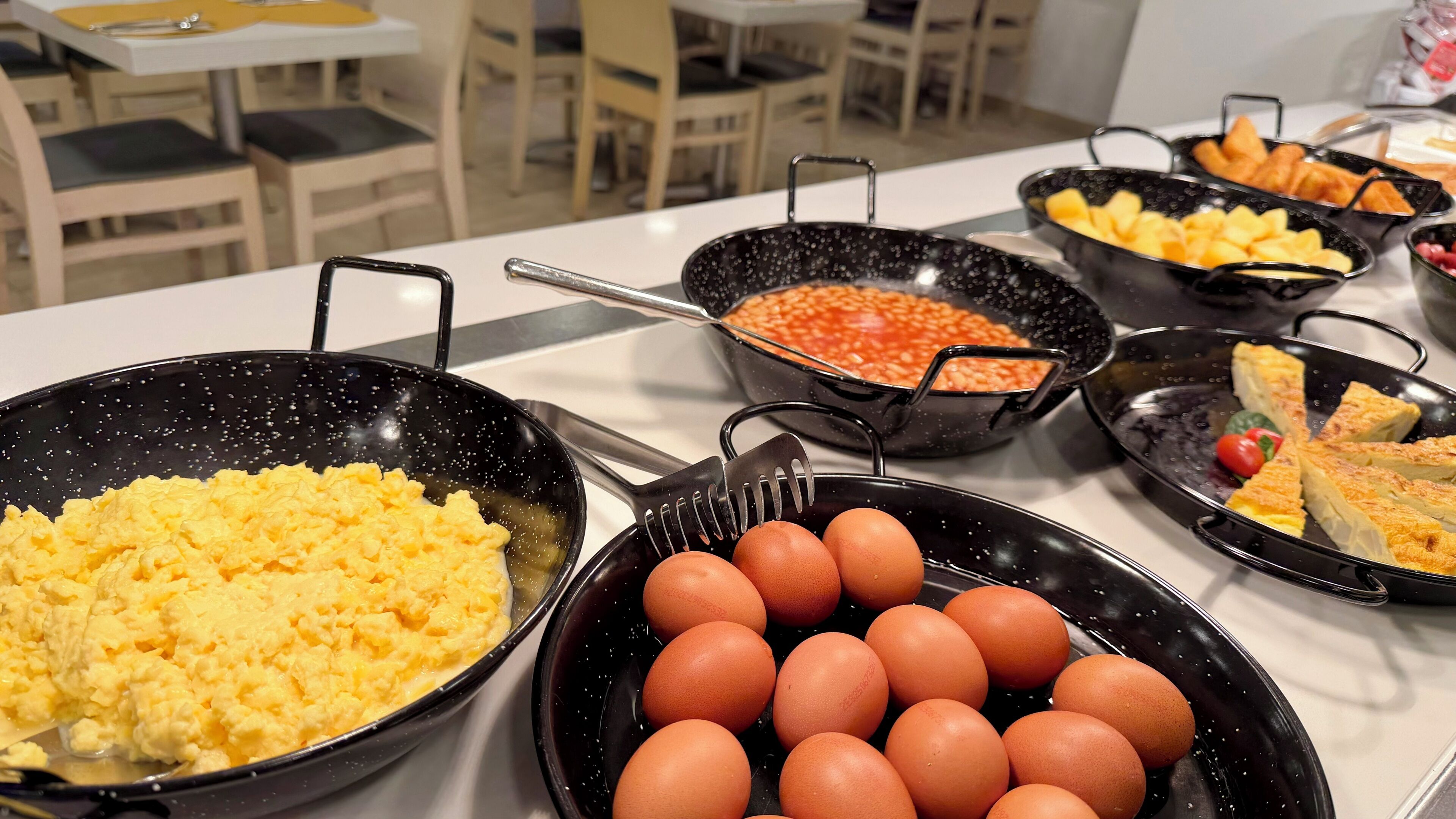 Een ontbijtbuffet met roerei, eieren en diverse gerechten.