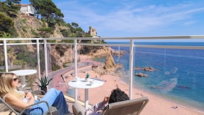 Un balcón con vista a una playa, un castillo y un litoral rocoso.