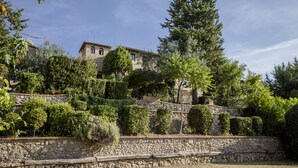 A stone-walled building with a rustic appearance, surrounded by lush greenery and trees. - Hotel Pescille by Double Hospitality (San Gimignano)