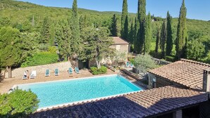A swimming pool with lounge chairs, surrounded by greenery and a hillside. - Hotel Pescille by Double Hospitality (San Gimignano)