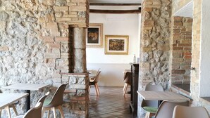 A rustic dining area with stone walls, wooden beams, and tiled flooring. There are several tables and chairs arranged for dining. - Hotel Pescille by Double Hospitality (San Gimignano)