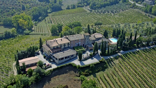 An aerial view of a vineyard estate with terraced vineyards, a central building with multiple rooms, and a swimming pool. - Hotel Pescille by Double Hospitality (San Gimignano)