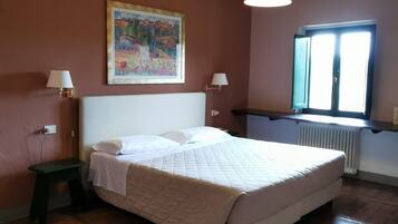Ein Schlafzimmer mit einem Bett, zwei Nachttischlampen, einem Bild an der Wand, einem Fenster mit Aussicht und einer Heizung.
