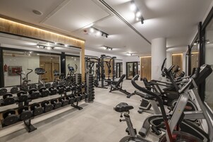 Un gimnasio moderno con diversos equipos de ejercicio, incluyendo cintas de correr, bicicletas estáticas y máquinas de pesas.