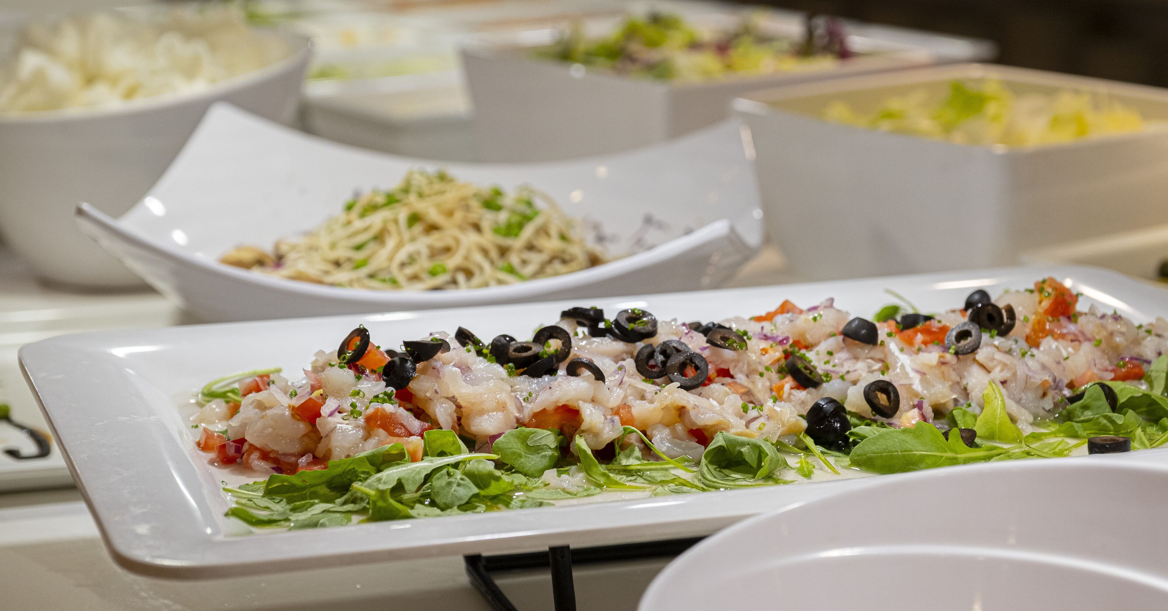 A buffet with various dishes including a seafood salad and pasta.