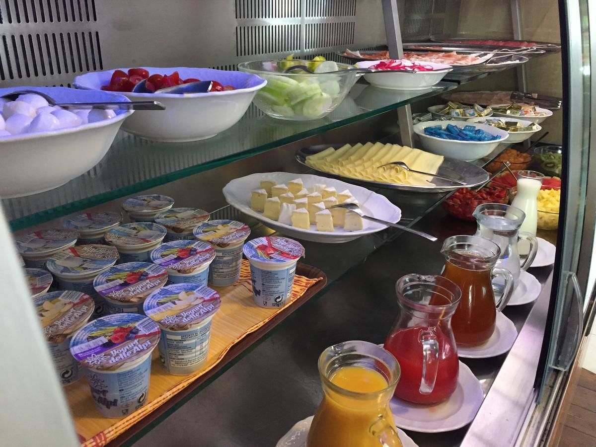 Un bufé con diversas opciones de comida, incluyendo yogur, frutas y jugos.