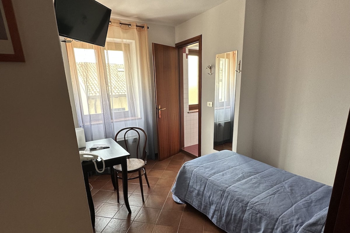 A bedroom with a bed, a desk, and a chair.