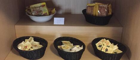 A display of various food items in baskets and bowls, including packaged snacks and bread.