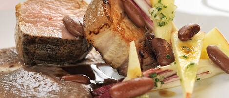 A plated dish with various food items, including a piece of meat, potatoes, and vegetables.