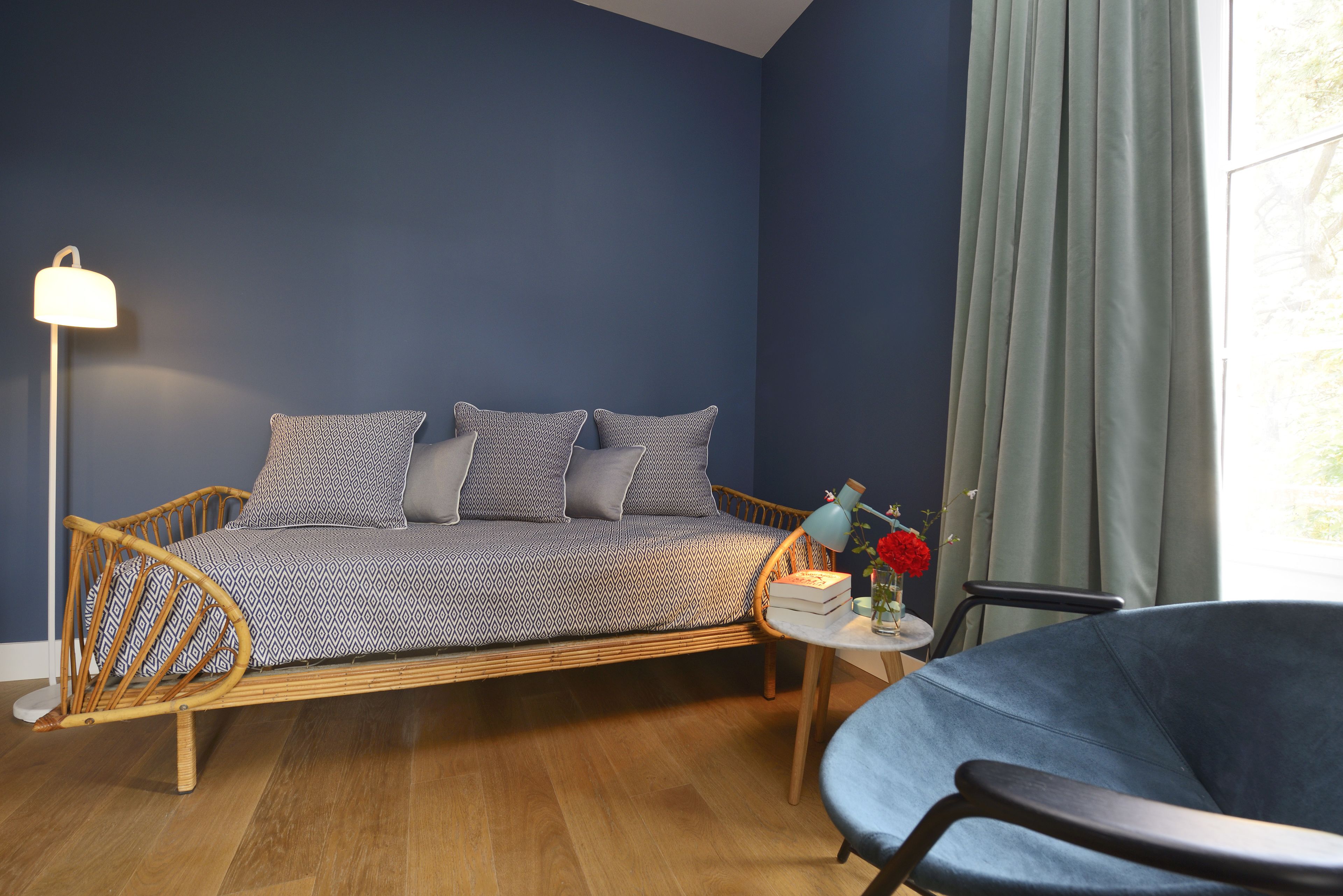 Een kamer met een bed, een stoel, een lamp en een raam met gordijnen.