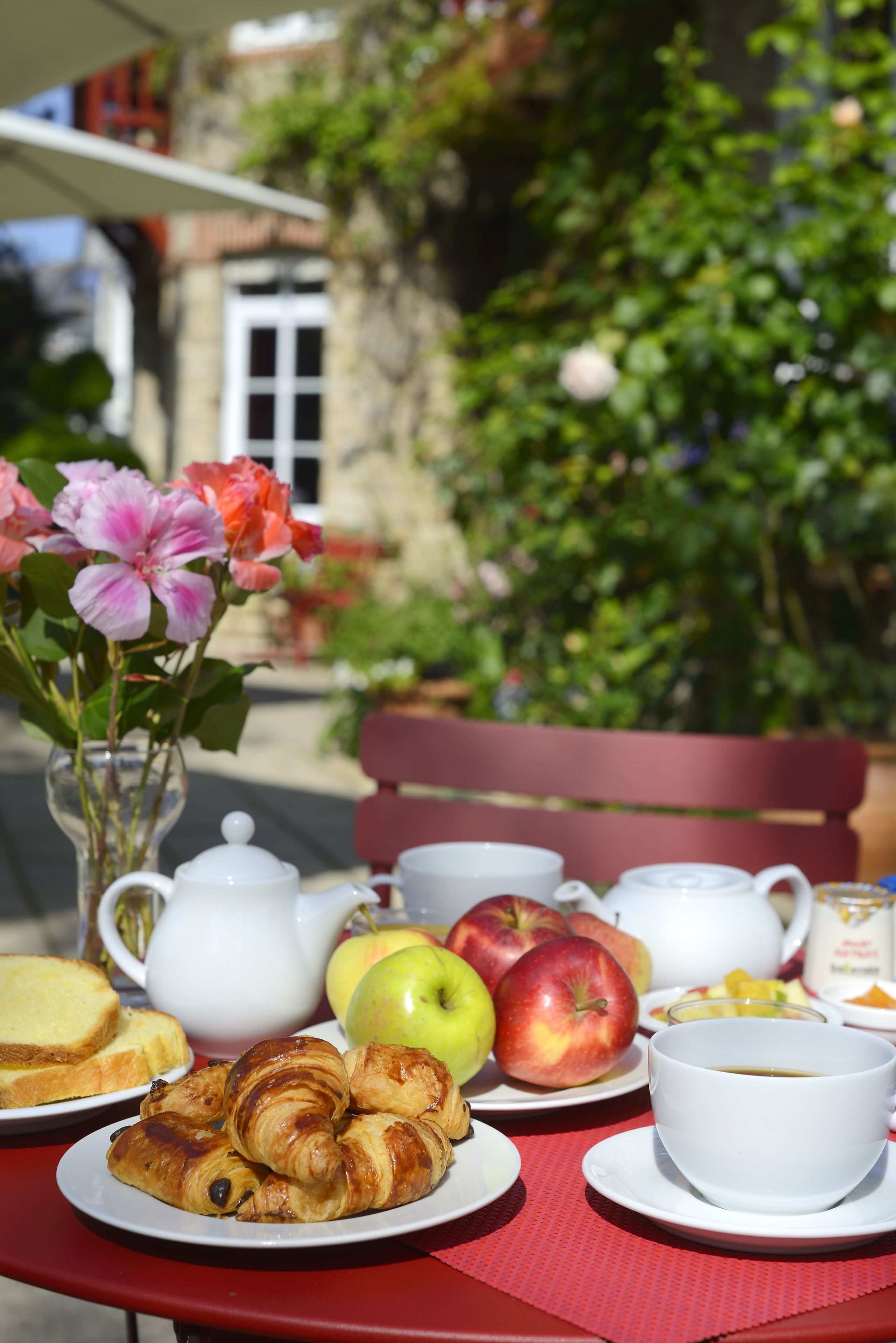 A table set with croissants, apples, and a teapot.