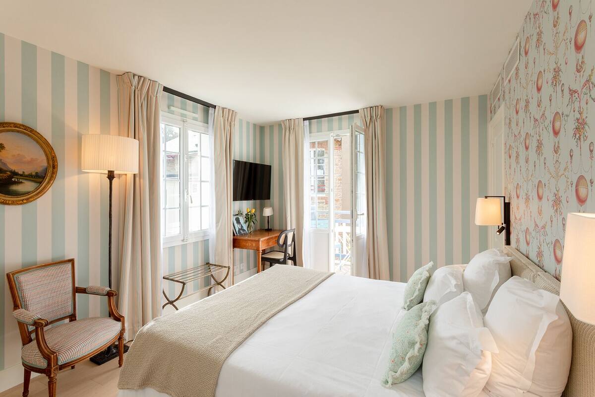 A hotel room with a bed, a desk, a chair, a TV, and curtains.