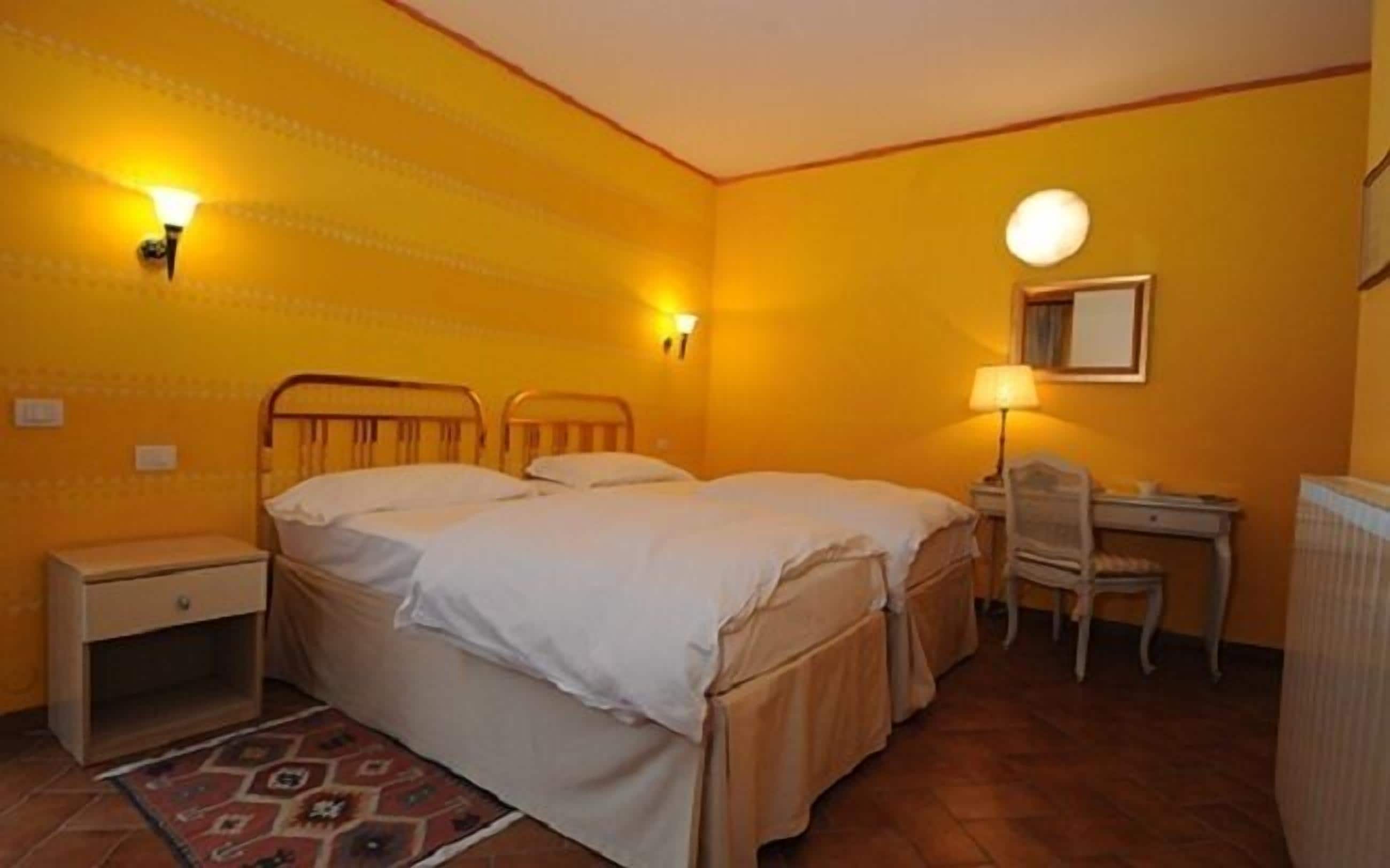 A room with two beds, a desk, a chair, and a lamp.