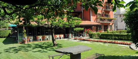 A courtyard with a stone table and benches, surrounded by a well-maintained lawn and flower beds.