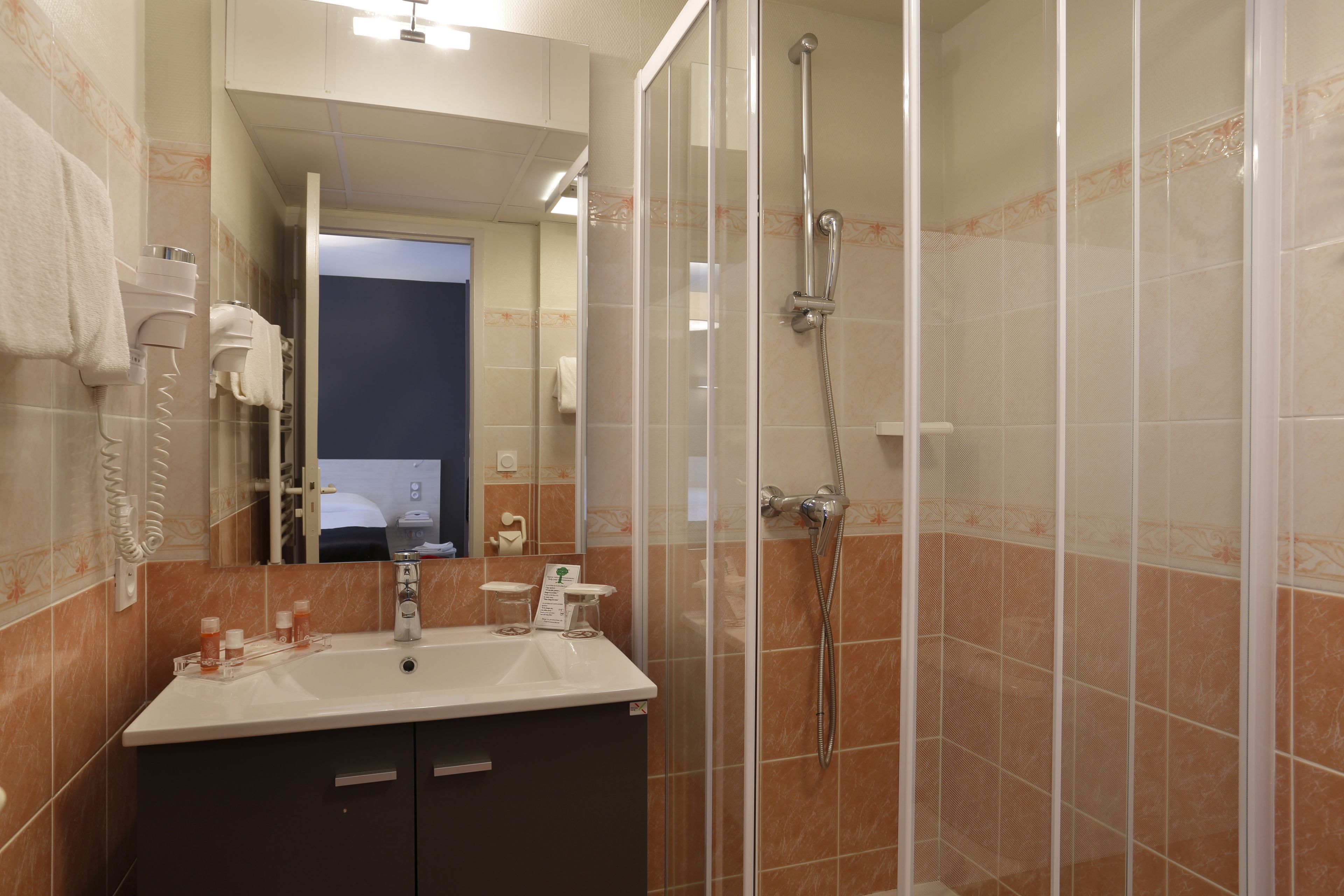 A bathroom with a glass-enclosed shower, a sink with a mirror, and a towel rack.