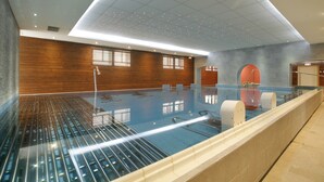 A modern indoor swimming pool with a tiled floor, a wooden wall, and a ceiling with recessed lighting. - The Originals City, Hôtel Les Thermes de l'Avenue (Dax)