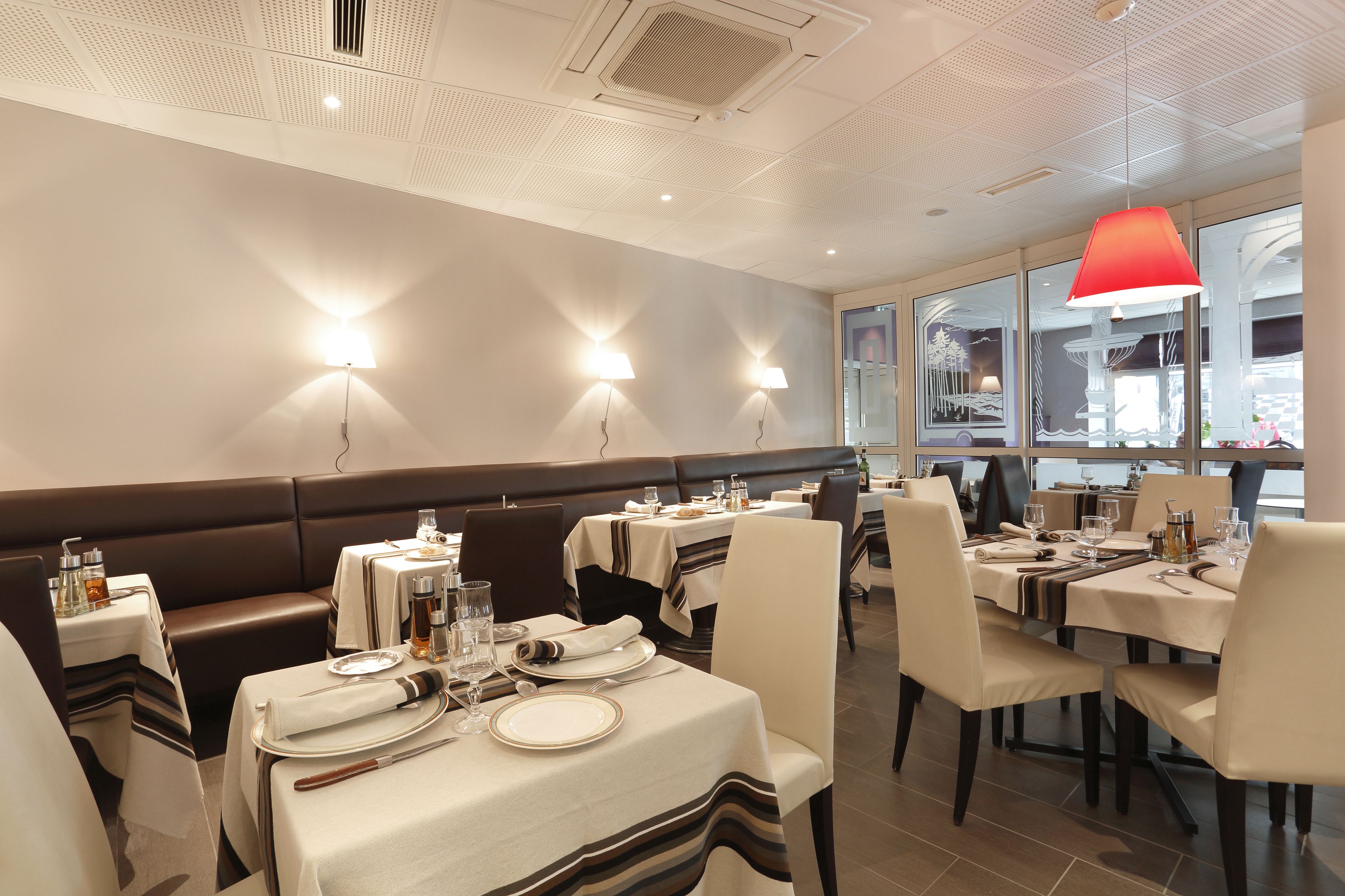 Un restaurante con cabinas y mesas, cada conjunto dispuesto con platos, cubiertos y vasos.