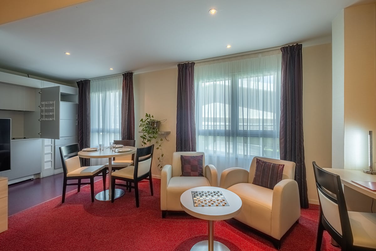 Ein modernes Wohnzimmer mit Essbereich, einer Couch, einem kleinen Tisch mit Schachbrett und einem Fernseher.