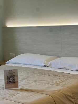 A bed with white bedding, a headboard, and a QR code sign on the floor. - Il Grifo Hotel e Bisteccheria Toscana (Montepulciano)