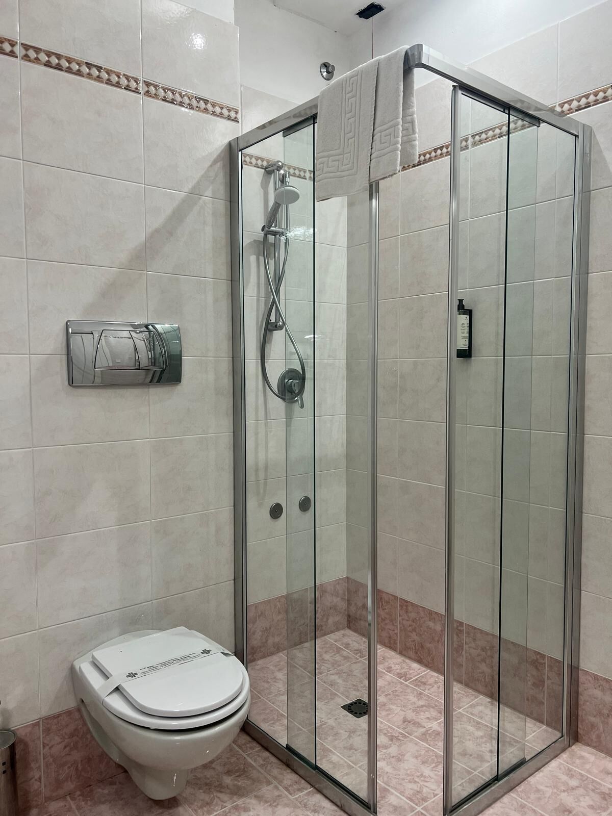 Ein modernes Badezimmer mit einer gläsernen Duschkabine, Toilette und Handtuchhalter.
