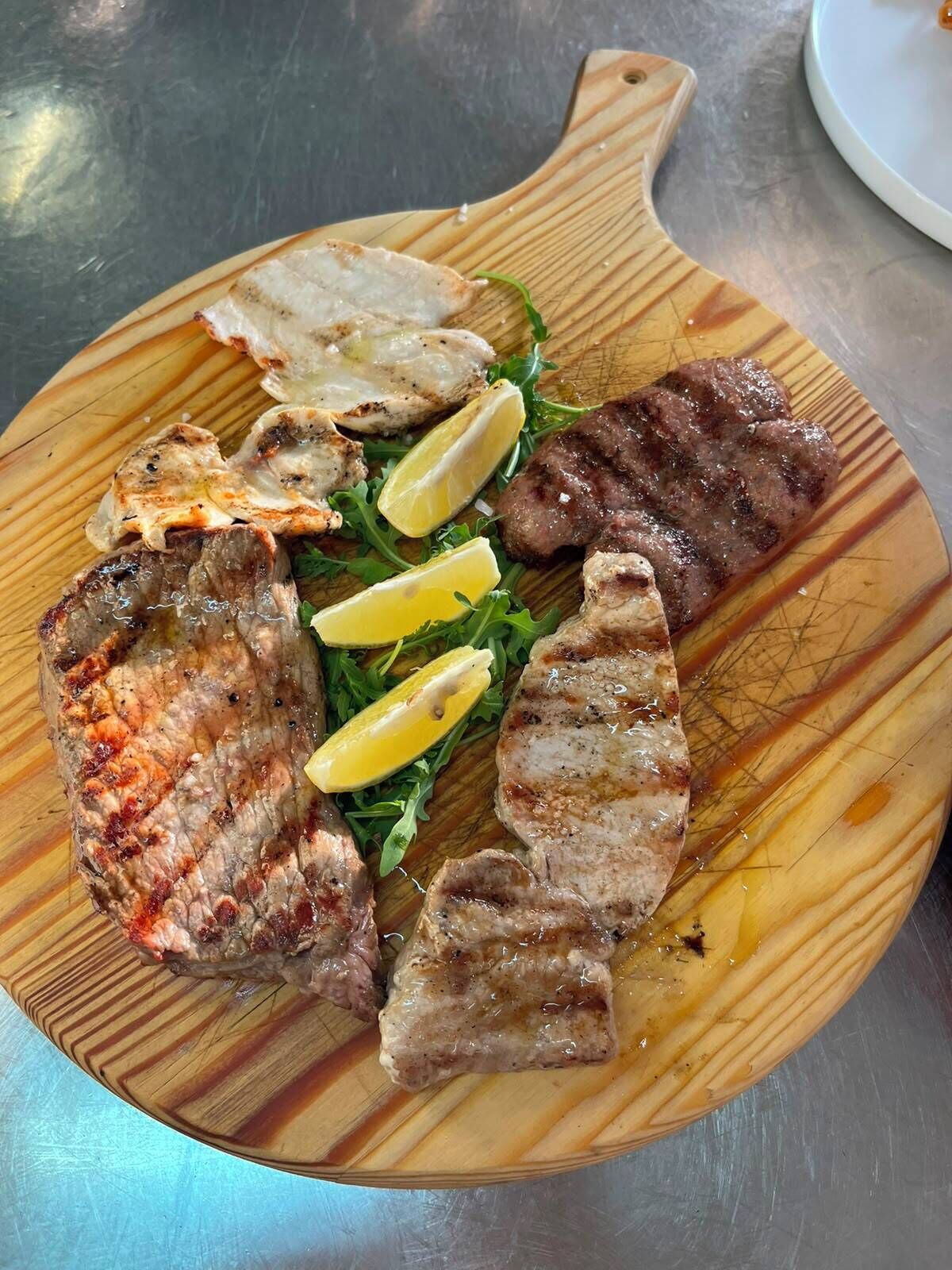 Une planche à découper en bois avec de la viande grillée et des tranches de citron.
