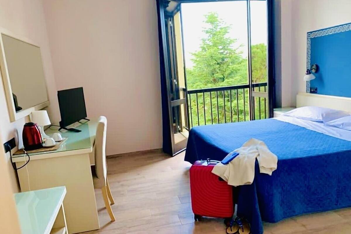 Una habitación de hotel con escritorio, computadora y cama con cubrecama azul.