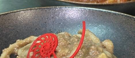 A close-up of a pasta dish with a decorative red element on top.