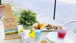 Una mesa con alimentos para el desayuno, incluyendo pasteles, una taza de café y un vaso de leche, con un cartel de bienvenida y una planta pequeña sobre la mesa.
