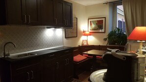 A compact kitchen with dark cabinets, a sink, and a dining area with a table and chairs. - Bed & Breakfast A Casa di Lia a Roma (Rome)