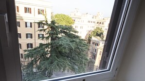 A window with a view of buildings and a tree. There is a bottle and two glasses on a small table. - Bed & Breakfast A Casa di Lia a Roma (Rome)
