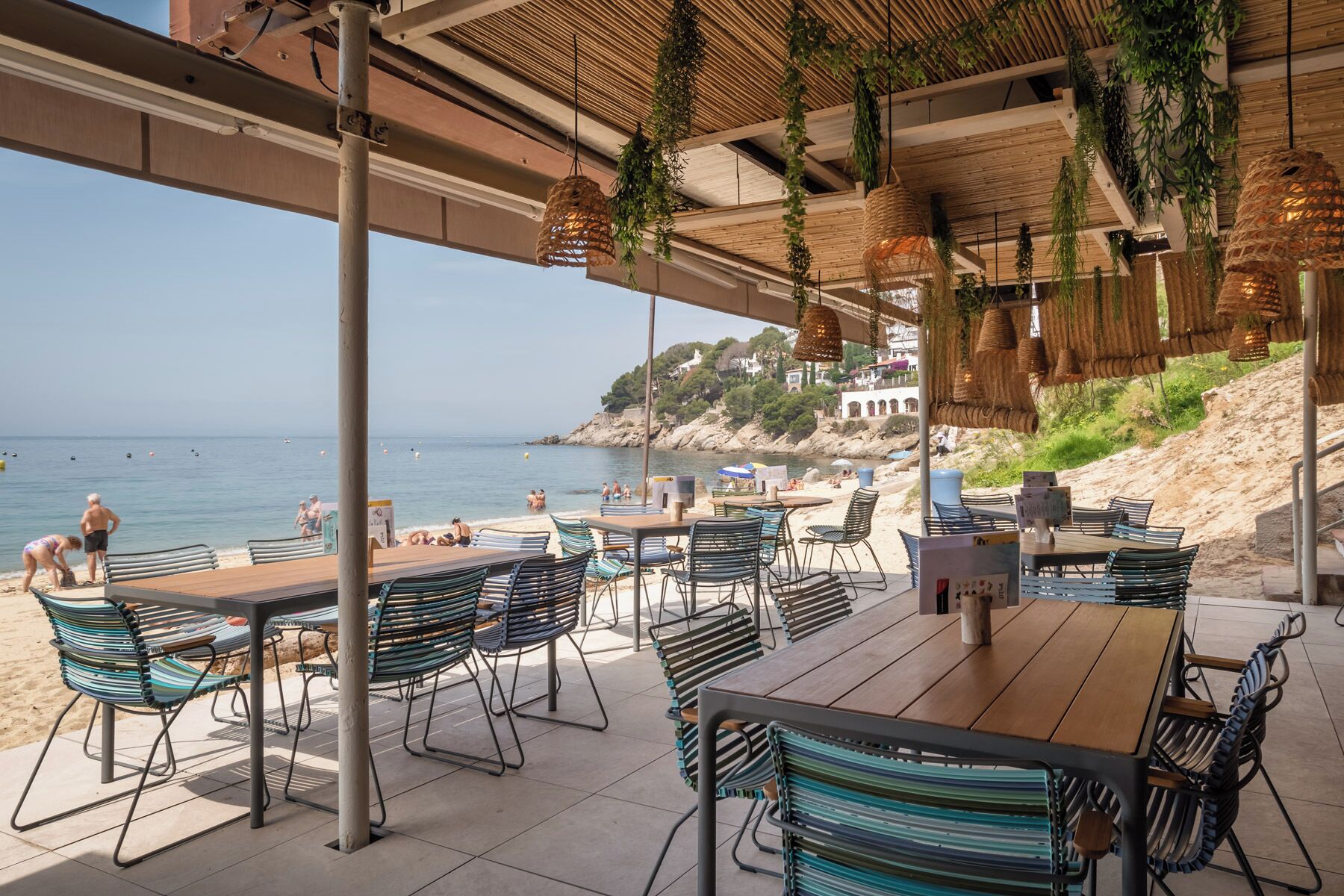 Un espace extérieur aménagé avec des tables et des chaises, offrant une vue sur une plage et la mer.