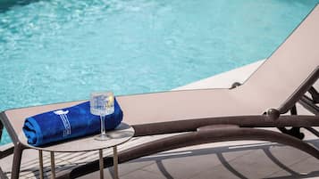Una silla de descanso junto a la piscina con una toalla y un vaso de agua.