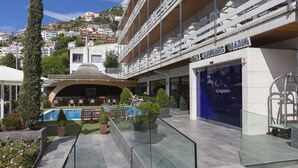 A hotel with a pool, outdoor seating, and a view of the surrounding hillside. - Canyelles Platja (Roses)