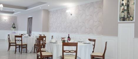 A dining area with round tables, wooden chairs, and a wine display.