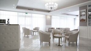 A modern hotel lobby with a chandelier, seating area, and a bar. - Hotel Leon (San Giovanni Rotondo)